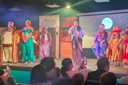 Kids in rehearsal or mid-performance during a youth musical theater production, showing emotion, teamwork, and excitement on stage.