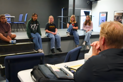 Students performing Frozen Jr. on stage with Arendelle castle backdrop and sparkling snow effects